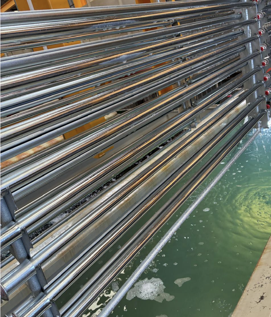 Freshly zinc-plated tubing on the rack line above the plating tank
